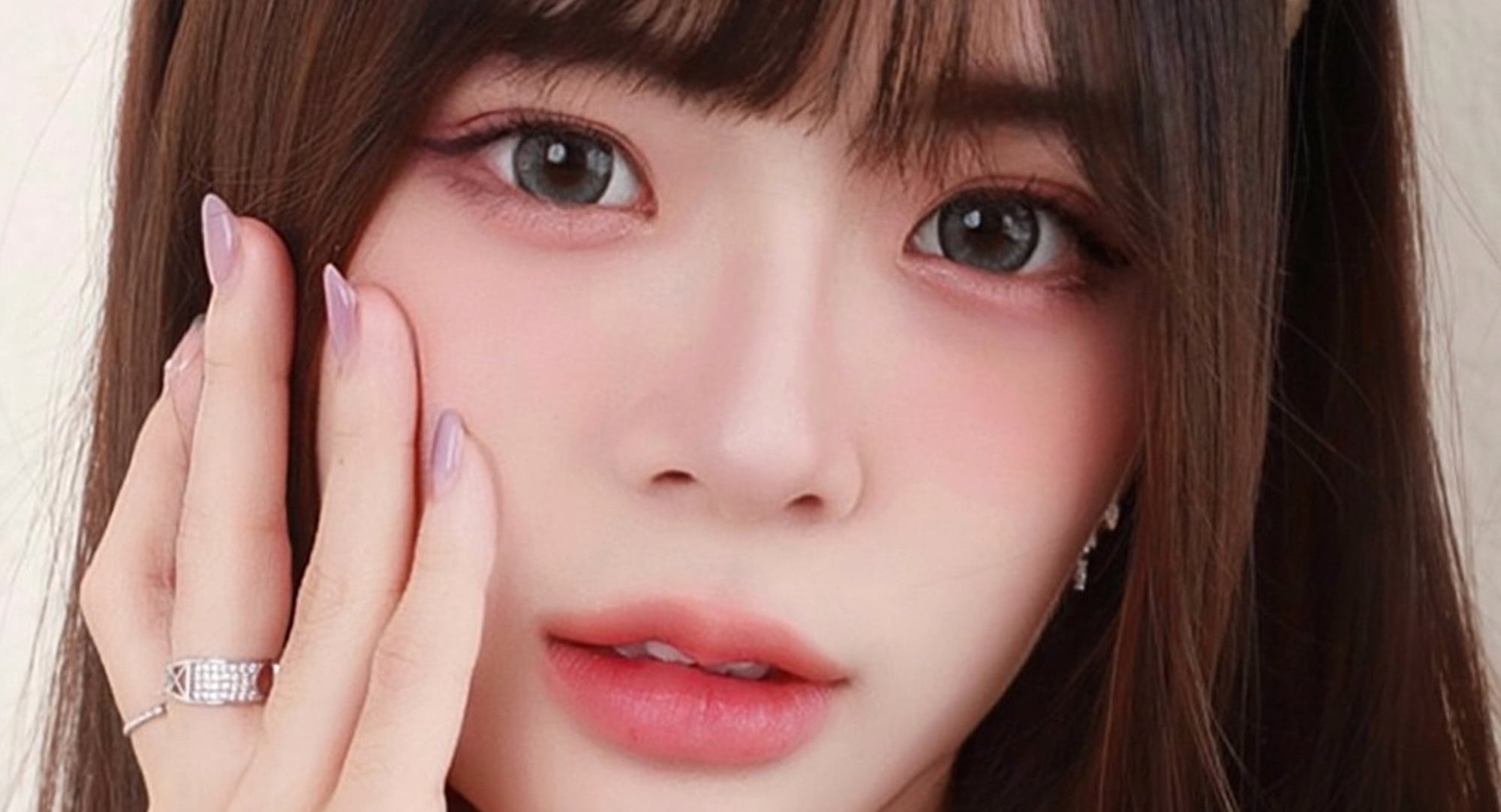 Close-up of a person with long hair and a hand on their face, featuring Exoticon contact lenses advertisement.